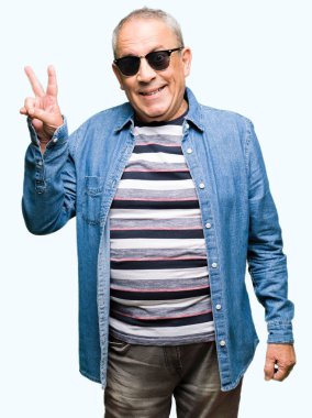 Denim ceket ve mutlu yüz zafer işareti yaparken kameraya göz kırpıyor ile gülümseyen güneş gözlüğü takan yakışıklı komuta sizde. İki numaralı.