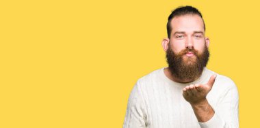 Bir öpücük el ile güzel ve seksi olmak hava üfleme kamera bakarak kış kazak giyen genç hipster adam. Aşk ifade.