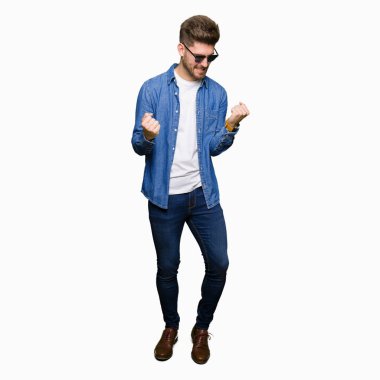 Gülümseyen ve başarı için çığlık denim ceket çok mutlu ve heyecanlı kaldırdı, silah ile kazanan jest yapıyor yakışıklı zarif delikanlı. Kutlama kavramı.