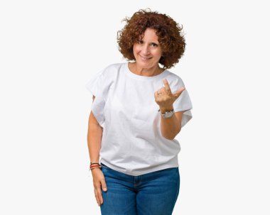 Beckoning gel burada mutlu ve gülümseyerek el davet ile jest izole arka plan üzerinde beyaz t-shirt giyen kadın güzel orta ager kıdemli