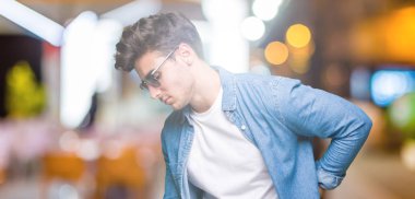 Genç yakışıklı adam giyen güneş gözlüğü izole üzerinde el ile geri, kas ağrısı dokunmadan acı sırt ağrısı, arka plan