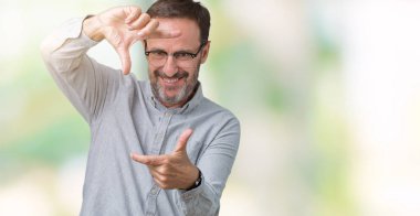 Elle yapma çerçeve ve parmakları ile mutlu yüz gülümseyen izole arka plan üzerinde gözlük takan yakışıklı orta yaş zarif komuta sizde. Yaratıcılık ve Fotoğrafçılık kavramı.