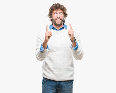 Adam model giyen kış kazak izole arka plan üzerinden hayran ve yukarıya bakıp parmakları ile işaret şaşırttı ve silah kaldırdı yakışıklı İspanyol.