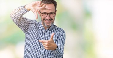 Elle yapma çerçeve ve parmakları ile mutlu yüz gülümseyen izole arka plan üzerinde gözlük takan yakışıklı orta yaş zarif üst düzey iş adamı. Yaratıcılık ve Fotoğrafçılık kavramı.