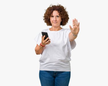 Kullanan orta ager üst düzey kadın, mesaj ile smartphone açık eliyle dur işareti ile ciddi ve kendine güvenen ifade, savunma jest yapıyor izole arka plan üzerinde