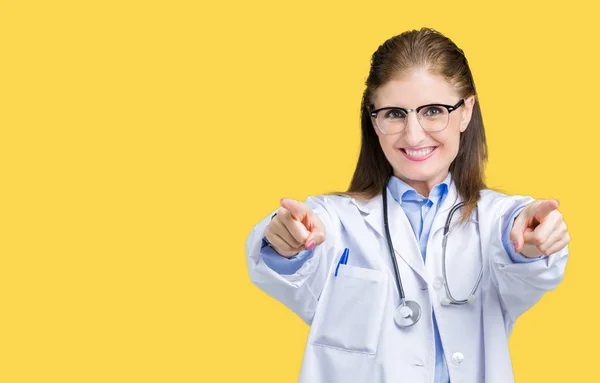 中年成熟的医生妇女穿着医疗外套在孤立的背景指向你和相机用手指 微笑着积极和开朗 — 图库照片