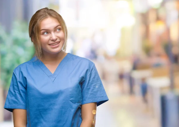 年轻的白种人护士穿外科医生制服在孤立的背景看一边与微笑的脸上 自然的表达 笑的自信 — 图库照片