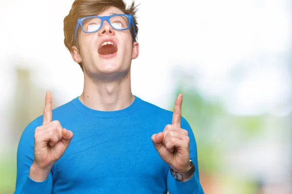 Joven Hombre Guapo Con Gafas Azules Sobre Fondo Aislado Asombrado —  Fotos de Stock