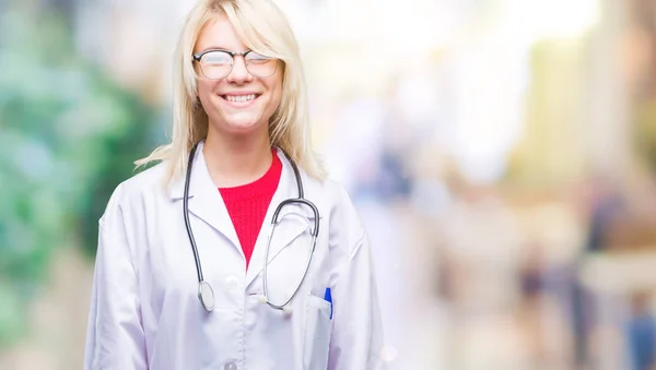 年轻美丽的金发医生妇女穿医疗制服在孤立的背景与一个愉快和凉爽的笑容在脸上 幸运的人 — 图库照片