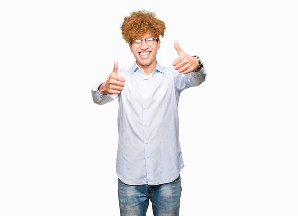 年轻英俊的商人戴着眼镜 赞成用手做积极的手势 竖起大拇指微笑 为成功而高兴 看着镜头 赢家的手势 — 图库照片