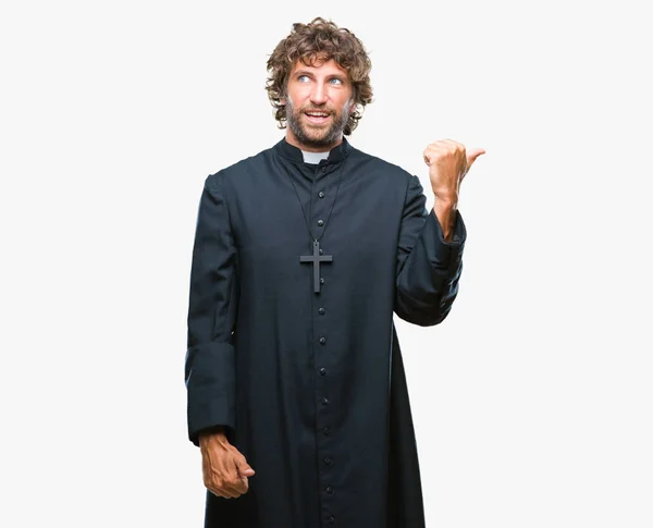 英俊的拉美裔天主教牧师男子在孤立的背景微笑着快乐的脸 并指向侧面与拇指向上 — 图库照片