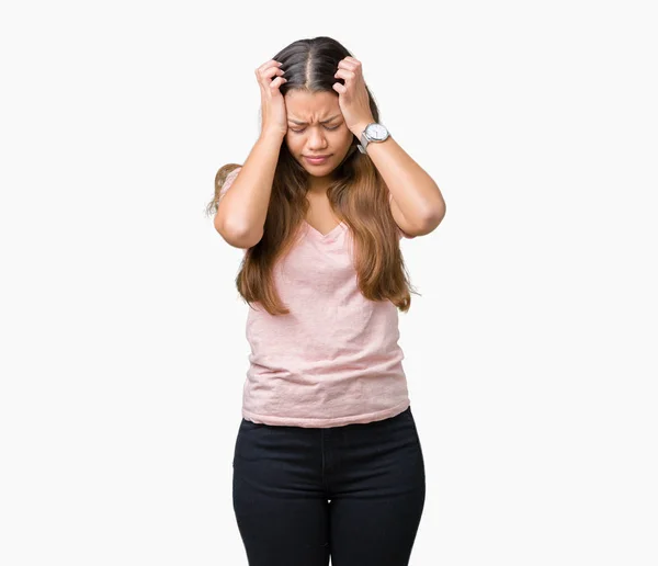 年轻美丽的黑发女人穿着粉红色的 T恤在孤立的背景下遭受头痛绝望和压力 因为疼痛和偏头痛 双手放在头上 — 图库照片