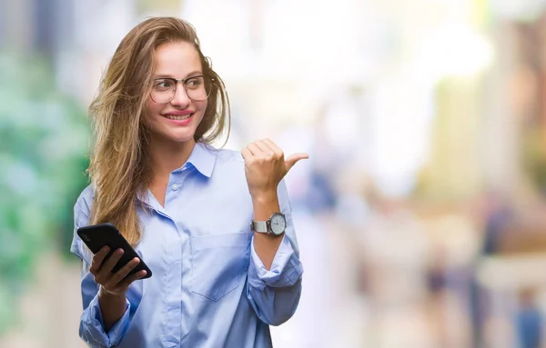 年轻美丽的金发女郎商业妇女使用智能手机在孤立的背景指向和显示与拇指面带笑脸微笑 — 图库照片