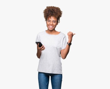 İşaret ve başparmak kadar mutlu yüz gülümseyen tarafı ile gösteren izole arka plan üzerinde akıllı telefon kullanan genç Afro-Amerikan kadın
