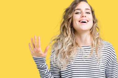 Güzel sarışın genç kadın giyiyor çizgili süveter gösterilen ve parmakları ile işaret izole arka plan üzerinde beş kendinden emin ve mutlu gülümseyerek iken numara.