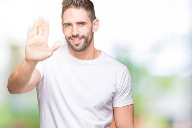 Yakışıklı adam beyaz t-shirt üzerine açık havada arka plan Waiving selam söyleyerek mutlu ve gülümseyen, dostça karşılama jest