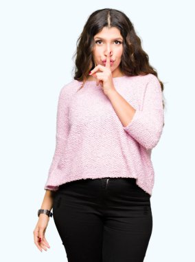 Dudaklarında parmak ile sessiz olmanı pembe kazak giyen genç güzel kadın. Sessizlik ve gizli kavramı.