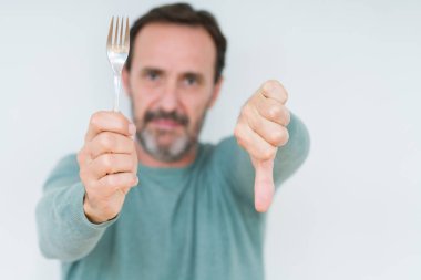 Komuta sizde kızgın yüzü, eksi işareti aşağı antipati başparmak ile gösterilen, ret kavramı ile izole arka plan üzerinde gümüş çatal tutan