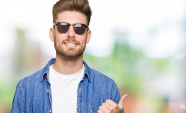 Hareketi el ile mutlu yaşasın yapıyor kot ceket giyen genç yakışıklı zarif adam. Kameraya bakarak başarı gösteren ile ifade onaylama.