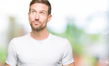 Yakışıklı adam görünümlü yan ve dik dik bakma uzağa düşünce gülümseyen casual beyaz t-shirt giyen.