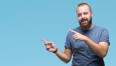 Genç beyaz hipster adam gülümseyerek ve iki elleri ve parmakları ile tarafına işaret kamera bakarak izole arka plan.