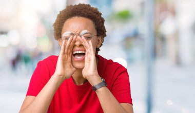 Eller ile kızgın yüksek sesle bağırarak izole arka plan üzerinde gözlük güzel genç Afro-Amerikan kadın ağzına