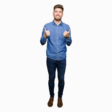 Genç yakışıklı sarışın adam el ile olumlu hareketi yaparken rahat kot gömlek başarı işareti giyiyor başparmak gülümseyen ve mutlu. Neşeli bir ifadeyle, kazanan jest kameraya bakıyor.