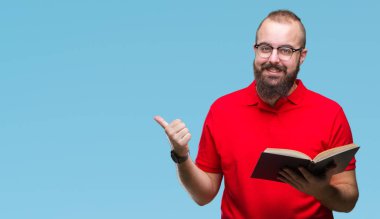 Gözlük takan ve işaret ve başparmak kadar mutlu yüz gülümseyen tarafı ile gösteren izole arka plan üzerine bir kitap okuma genç hipster adam