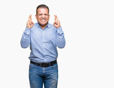 Orta yaş Arap iş adamı geçiş parmakları umut ve gözler gülümseyen izole arka plan üzerinde kapalı. Şans ve batıl kavramı.