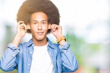 Afrikalı-Amerikalı genç afro saçlı gülen çekerek kulaklı parmaklarıyla, komik jest. Seçmelere sorun
