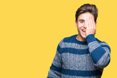 El yüz ve sürpriz duygu kendinden emin gülümseme ile tek gözüyle kapsayan izole arka plan üzerinde genç yakışıklı adam.