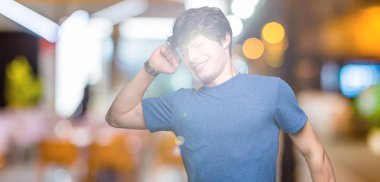 Üzerinde mavi t-shirt giyen genç yakışıklı adam arka plan geri uzanan izole, yorgun ve rahat, Uykulu ve erken sabah esneme