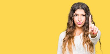 Beyaz kazak giyen genç güzel kadın parmağını ve kızgın ifade ile işaret