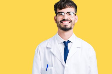 Yüzünde mutlu ve güzel bir gülümseme ile izole arka plan üzerinde beyaz önlük giyen genç profesyonel bilim adamı. Şanslı kişi.