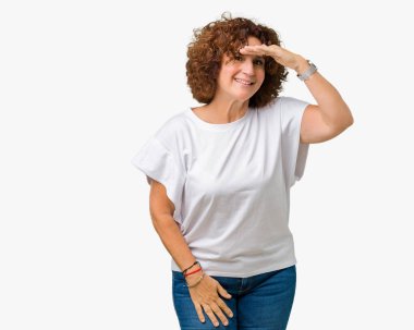 Üzerinde beyaz t-shirt giyen güzel orta ager üst düzey kadın arka plan çok mutlu ve gülümseyen uzakta el ile üzerine kafa seyir izole. Arama kavramı.