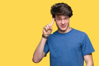 Mavi t-shirt üzerinde izole giyen genç yakışıklı adam arka plan bir parmak, harika bir fikir ya da düşünce, iyi hafıza ile baş gösteren gülen