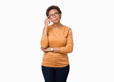 Genç güzel Afrikalı-Amerikalı kadın gözlük ile izole arka plan üzerinde çene düşünme hakkında soru, dalgın ifade ver. Düşünceli yüzüyle gülümsüyor. Şüphe kavramı.