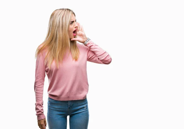 年轻美丽的金发碧眼的女人穿着粉红色的冬季毛衣在孤立的背景大喊和尖叫着一边与手在嘴 沟通理念 — 图库照片