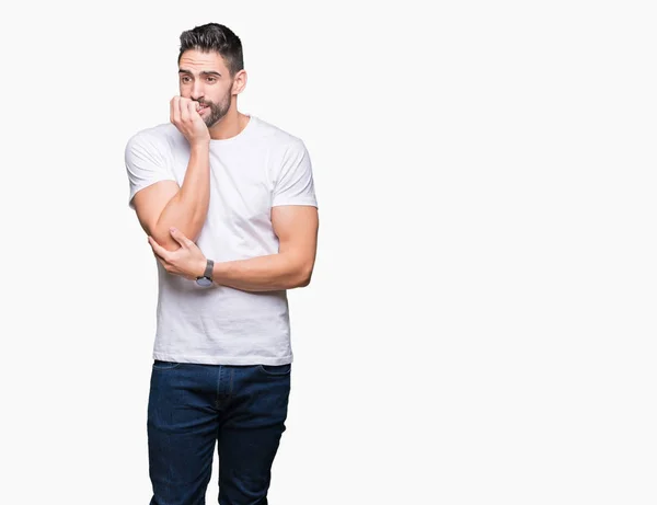年轻男子穿着休闲白色 T恤在孤立的背景看起来紧张和紧张的手在嘴咬指甲 焦虑问题 — 图库照片