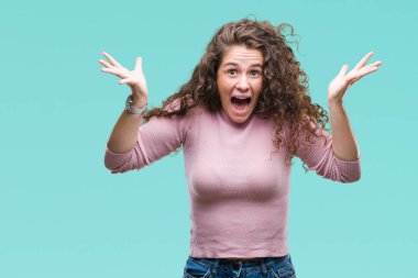 Güzel esmer kıvırcık saçlı Genç kız giyiyor pembe kazak üzerinde arka plan çılgın kutlama izole ve başarı için kaldırdı kollarını açarak hayret ve açık gözleri çığlık heyecanlı. Kazanan kavramı