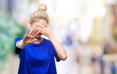 Üzerinde mavi t-shirt giyen genç güzel sarışın ve mavi gözlü kadın izole elleriyle gözlerini kapsayan arka plan ve stop jest ile acı ve korku ifadesi. Utandım ve negatif kavramı.