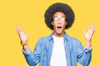 Çılgın ve silah ile başarı için hayran kutluyor gözlük takan afro saçlı genç Afro-Amerikan adam kaldırdı ve açık gözleri çığlık heyecanlı. Kazanan kavramı