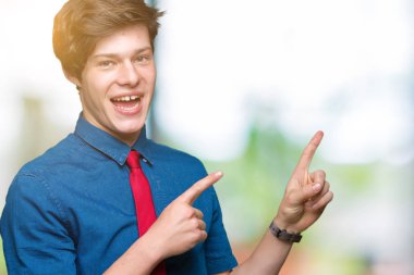 Gülümseyen ve iki elleri ve parmakları ile tarafına işaret kamera bakarak izole arka plan üzerinde kırmızı kravat giyen genç yakışıklı iş adamı.