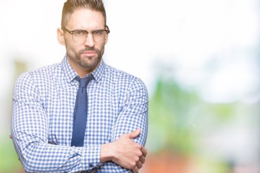 İzole arka plan şüpheci ve çapraz kolları olan yüzündeki gergin, onaylamayan ifade gözlüklü genç iş adamı. Negatif kişi.