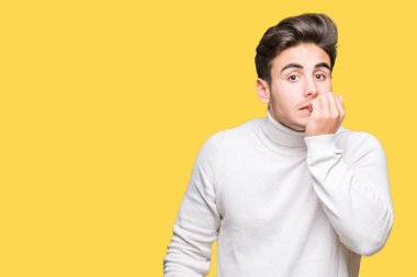 Genç yakışıklı adam stresli ve gergin ile izole arka plan üzerinde boğazlı kazak giyen tırnak ısırma dudaklarından eller. Anksiyete sorunu.