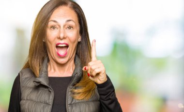 Kış yelek işaret parmağı ile başarılı fikir giyen güzel orta yaş kadın. Çıktıktan ve mutlu. Bir numara.