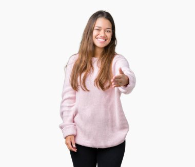 Tebrik ve konuksever dost sunan karşılıklı gülümseyen izole arka plan üzerinde pembe kış kazak giyen genç güzel esmer kadın. Başarılı iş.