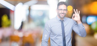 İzole arka plan el ve parmaklar ok işaretiyle yapıyor olumlu gülümseyen üzerinde gözlük takan genç iş adamı. Başarılı ifade.