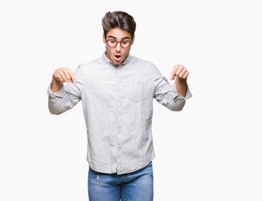 Genç yakışıklı adam gözlük izole üzerinde işaretleme aşağı reklam, sürpriz yüz ve açık ağız gösterilen parmakları ile arka plan