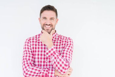 Emin çapraz kollar ve çeneme kaldırdı el ile gülümseme ile kameraya bakarak izole arka plan üzerinde gömlek giymiş yakışıklı delikanlı. Pozitif düşünce.